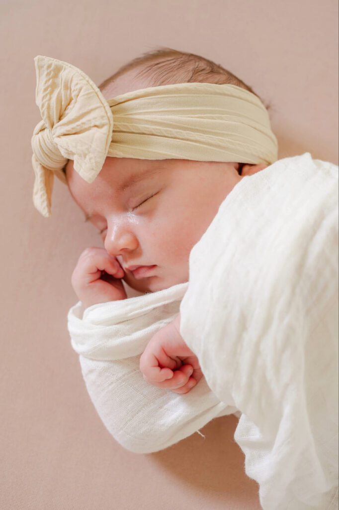 Baby girl swaddled sleeping with big bow